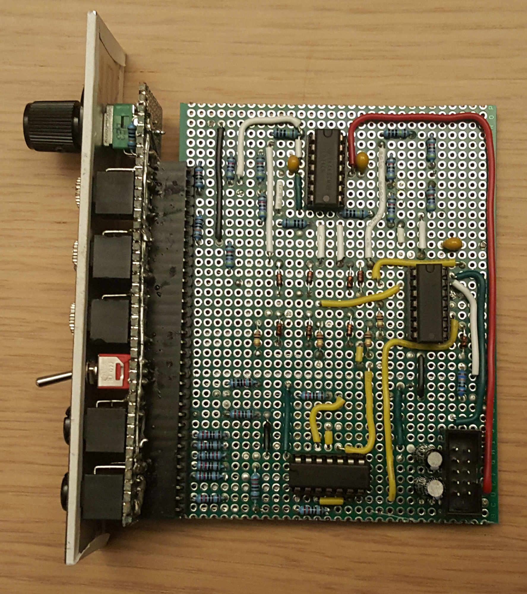 Side view of Compara4 module prototype: resistors, capacitors, diodes and integrated circuit chips are spread over a green prototype board. Jumper cables in various colours run around the board and make (mostly) vertical lines.